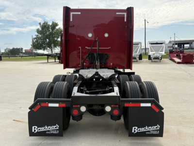 Peterbilt 579 rear view showing fifth wheel, dual rear axles, mud flaps with Bruckner's branding, and red sleeper cab in the background.