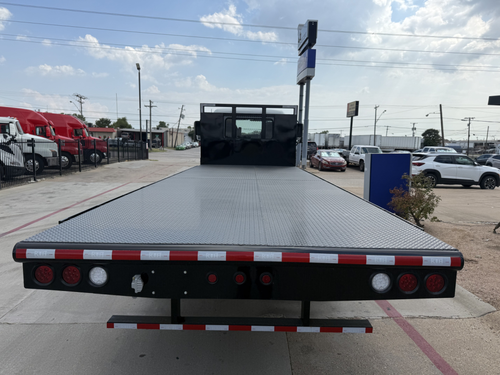 Flatbed truck platform on a new Mack MD6 with rear view showing reflective safety tape, lighting, and rear bumper.