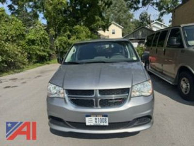 Front view of a 2016 Dodge Grand Caravan SE minivan, silver color, license plate visible, parked on a street.