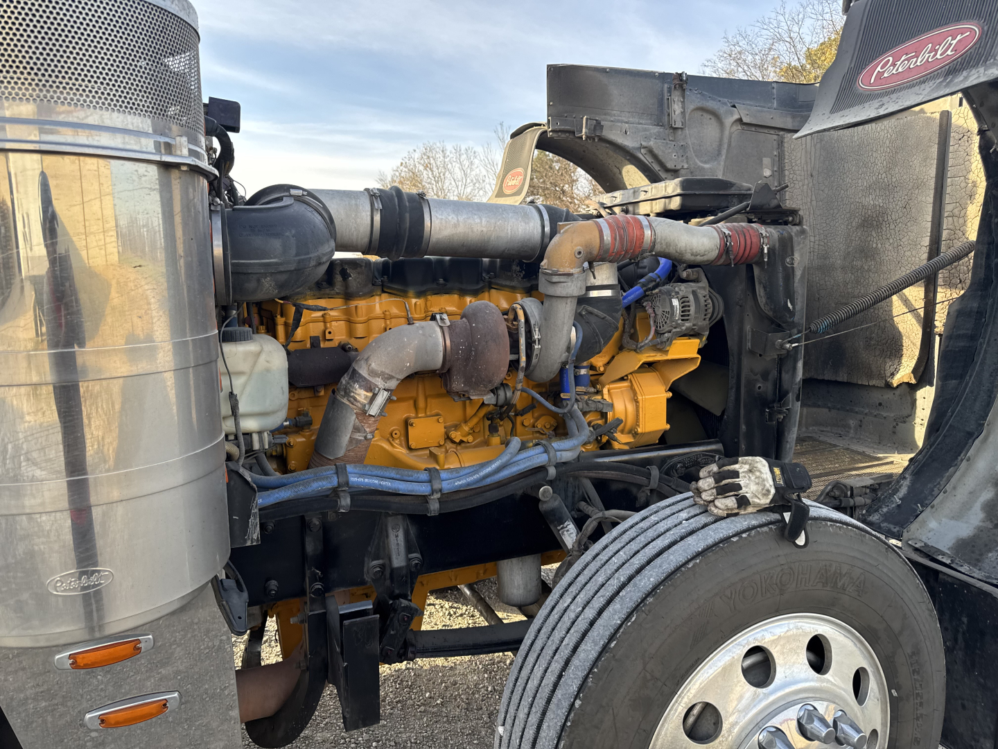 Peterbilt 379X engine bay showing large diesel V-engine with yellow blocks and chrome exhaust manifold, air intake, and cooling components.