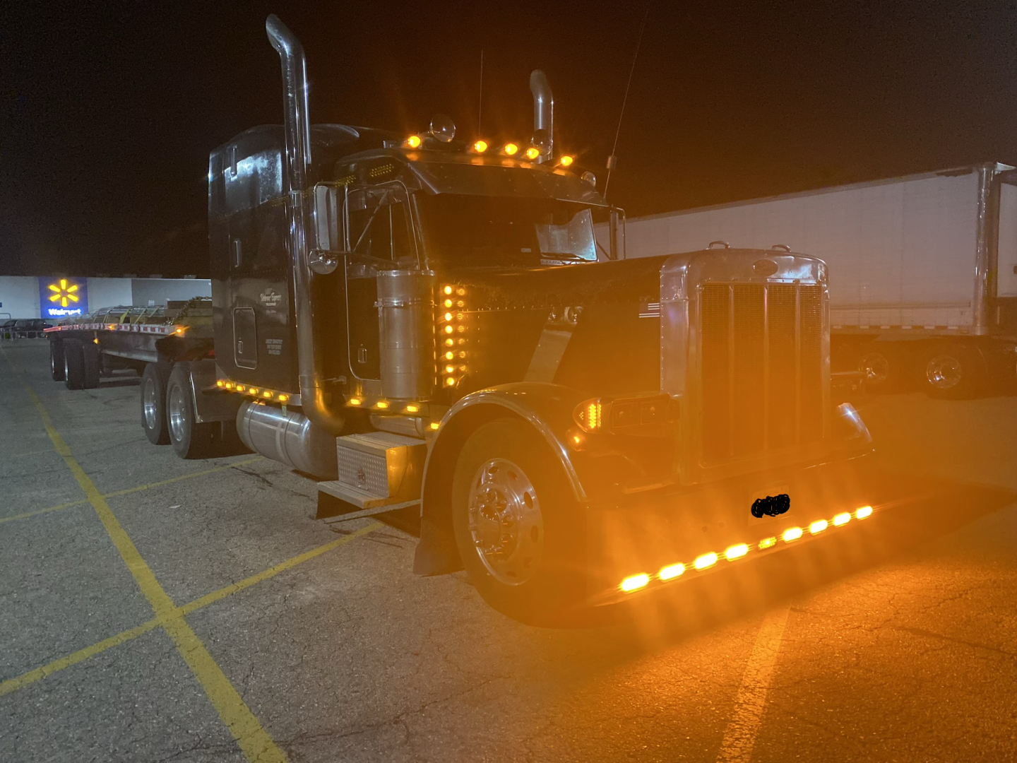 Peterbilt 379X conventional sleeper truck with chrome exhaust stacks, large front grille, and amber cab lights visible at night.