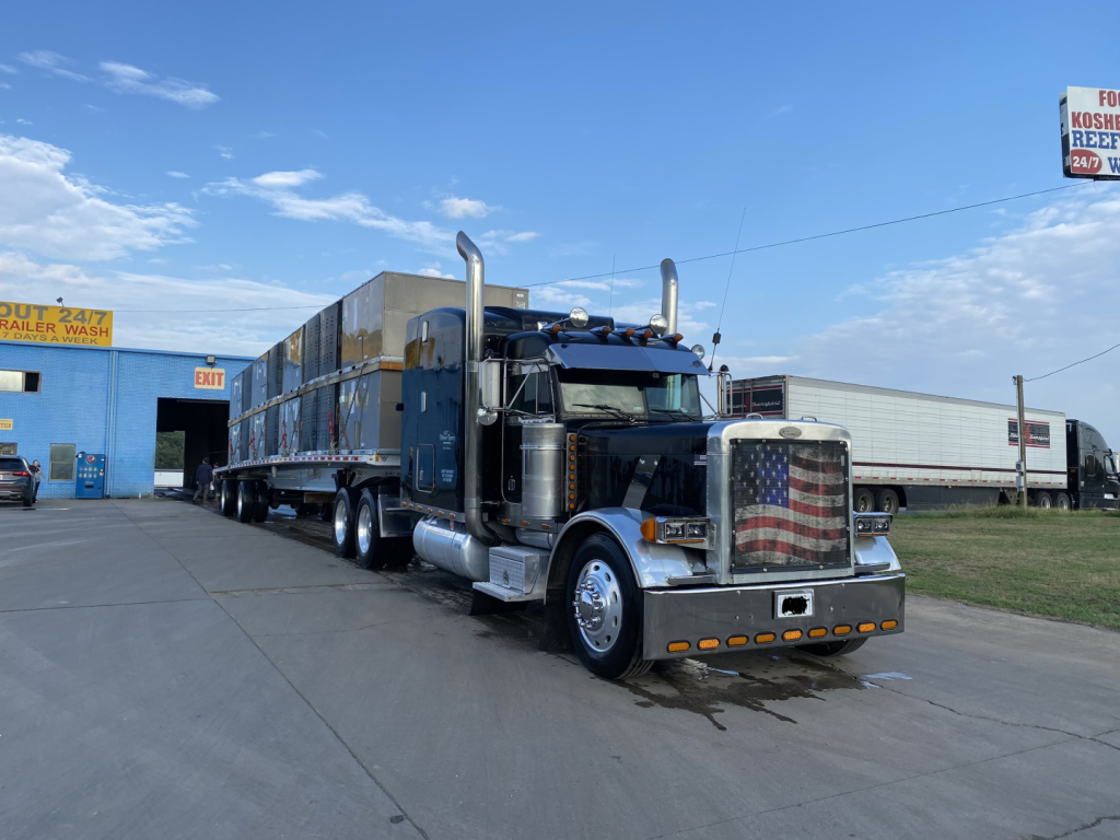 Peterbilt 379X conventional sleeper truck in blue with chrome stacks and large front grille, parked at a truck lot.