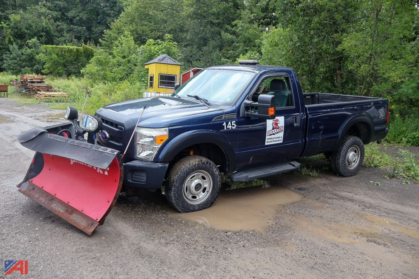Ford F-350 Super Duty pickup with snow plow attachment, single rear wheel, dark blue cab and bed, front plow resting on ground, decals on door, 4x4 badge.