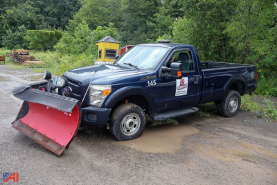 Ford F-350 Super Duty pickup with snow plow attachment, single rear wheel, dark blue cab and bed, front plow resting on ground, decals on door, 4x4 badge.
