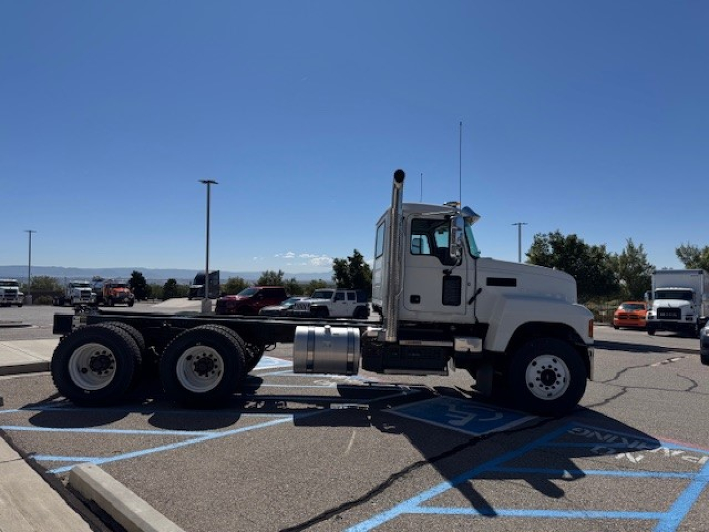 Truck tractor side view showing Mack PI64 cab and chassis with dual rear axles in a parking lot.