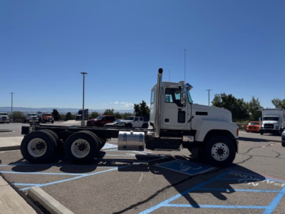 Truck tractor side view showing Mack PI64 cab and chassis with dual rear axles in a parking lot.