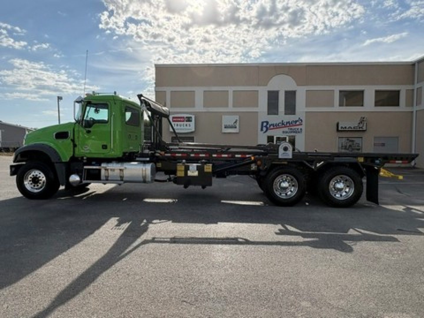 Green Mack GR64F roll-off truck side profile showing chassis and flatbed with three axles.