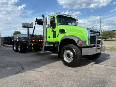 Green Mack GR64F truck with a lowboy trailer, front three-quarter view showing cab, chrome grille, and large headlights.