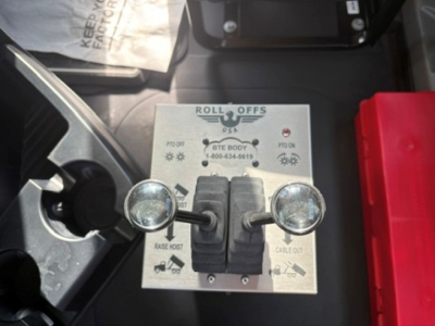Dashboard panel showing Roll Offs controls with two toggle levers and circular indicator lights in a Mack truck cab.