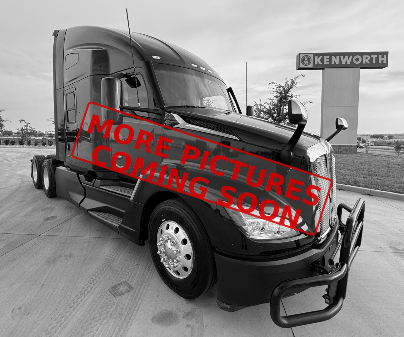 Kenworth T680 conventional sleeper truck in service condition showing front bumper and cab with Kenworth sign in background.