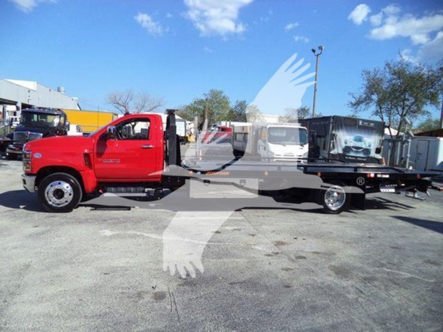 Chevrolet Silverado 6500HD rollback truck in red cab and black rollback bed, side view with flatbed and tow equipment
