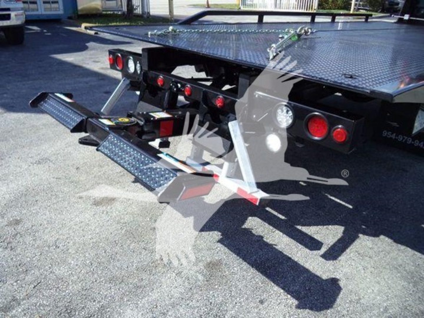 Truck bed showing hydraulic ramps and rear bumper on a rollback tow truck.