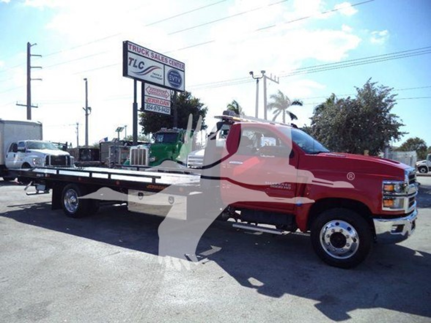 Chevrolet Silverado 6500HD rollback tow truck in red and white with flatbed, side view showing cab and long flatbed.