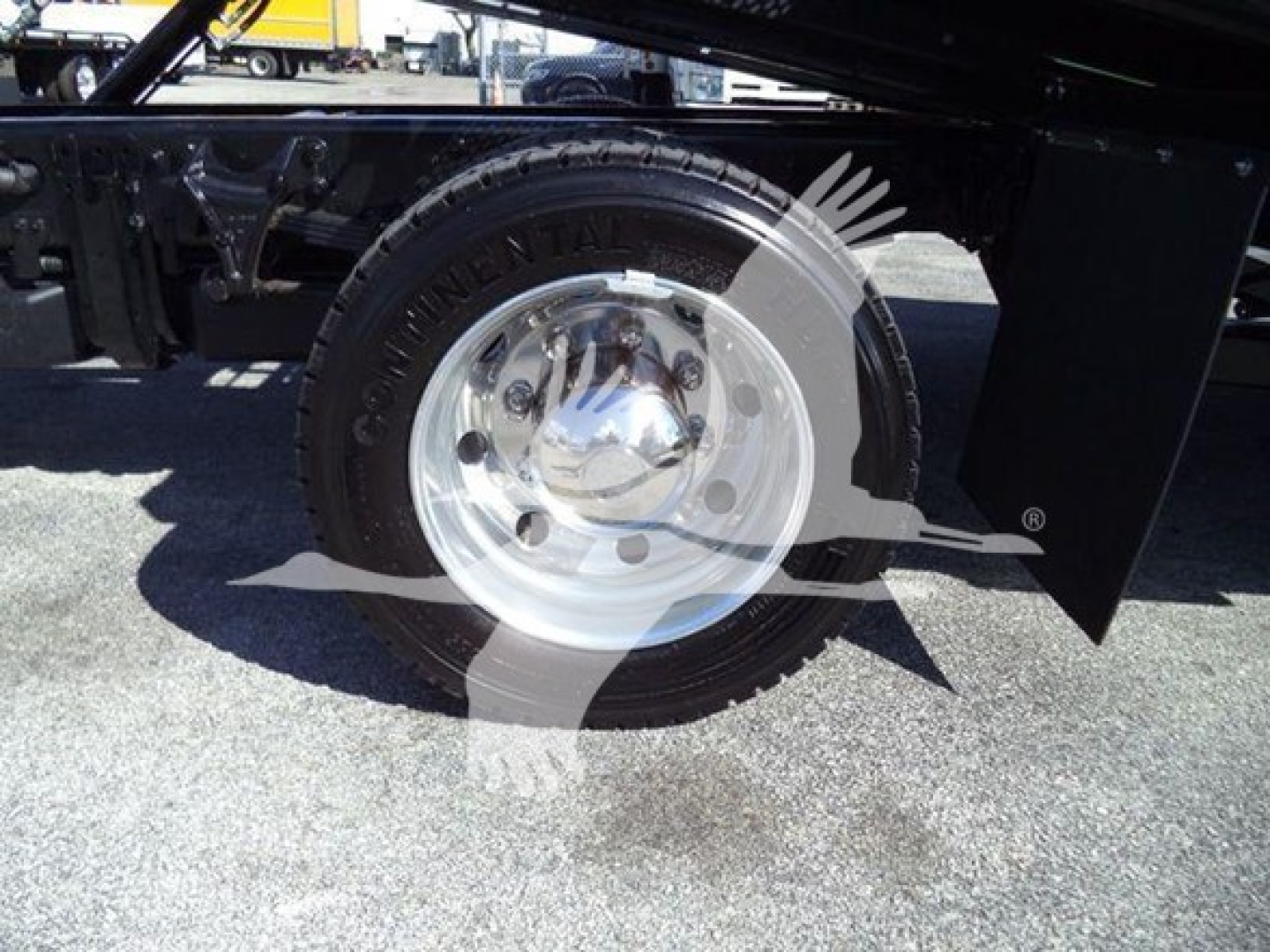 Truck wheel and tire on Silverado 6500hd chassis showing Goodyear or Uniroyal style wheel with chrome hubcap, undercarriage and black frame visible.