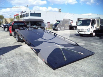 Chevrolet Silverado 6500HD rollback truck with long low-profile flatbed in dealership lot.