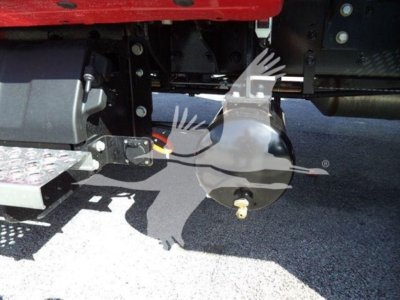 Truck undercarriage showing towing equipment and circular air tank/compartment with bolt and fuel line visible.