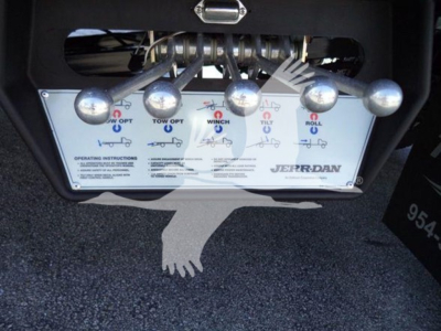 Truck control panel showing tow/winch/tilt/roll controls with labels and icons, brand 'Jerr-Dan' visible, levers and graphics on a metal plate.