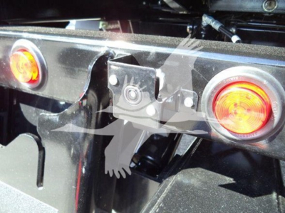Rear view of a rollback truck hitch area with two red circular taillights and a central mounting plate; partial view of a hitch receiver and metal frame.