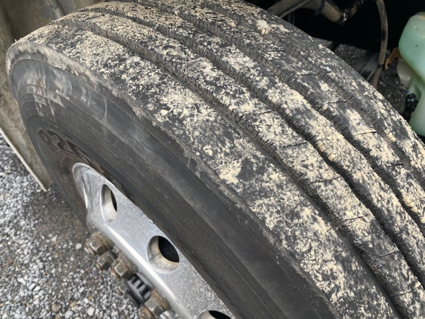 Truck wheel and tire close-up showing tread with dust and dirt on the Freightliner M2-106 component bay.