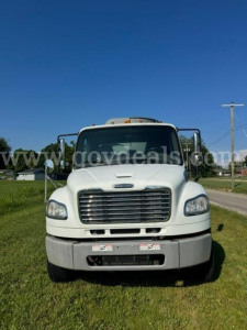 Front view of a white 2013 Freightliner M2 truck with grille, bumper, and windshield; visible license plate area and stock number sticker.