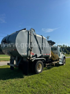 Truck-mounted vacuum tank tanker on a Freightliner M2 with rear view showing cylindrical tank and hoses.