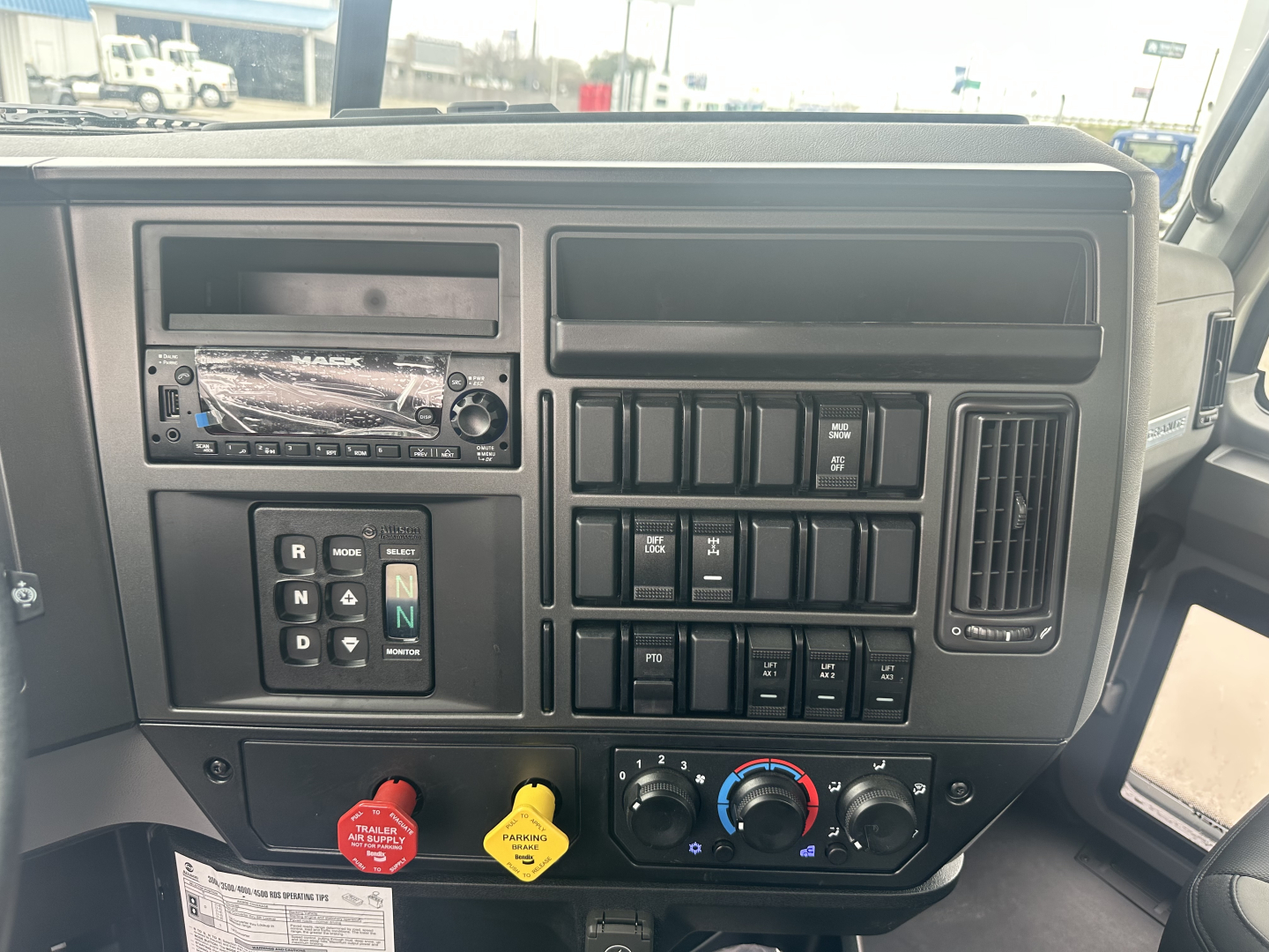 Truck dashboard with infotainment head unit, multiple switches, climate controls, and gear selector in view