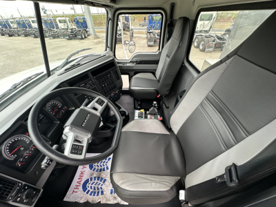 Truck cab interior of a 2026 Mack GR64F showing steering wheel, dashboard, driver seat, and passenger seat; visible controls and center console.