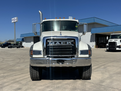 Mack GR64F dump truck front view showing large chrome grille with MACK lettering and bumper, heavy-duty tires, clear windshield, and side mirrors.