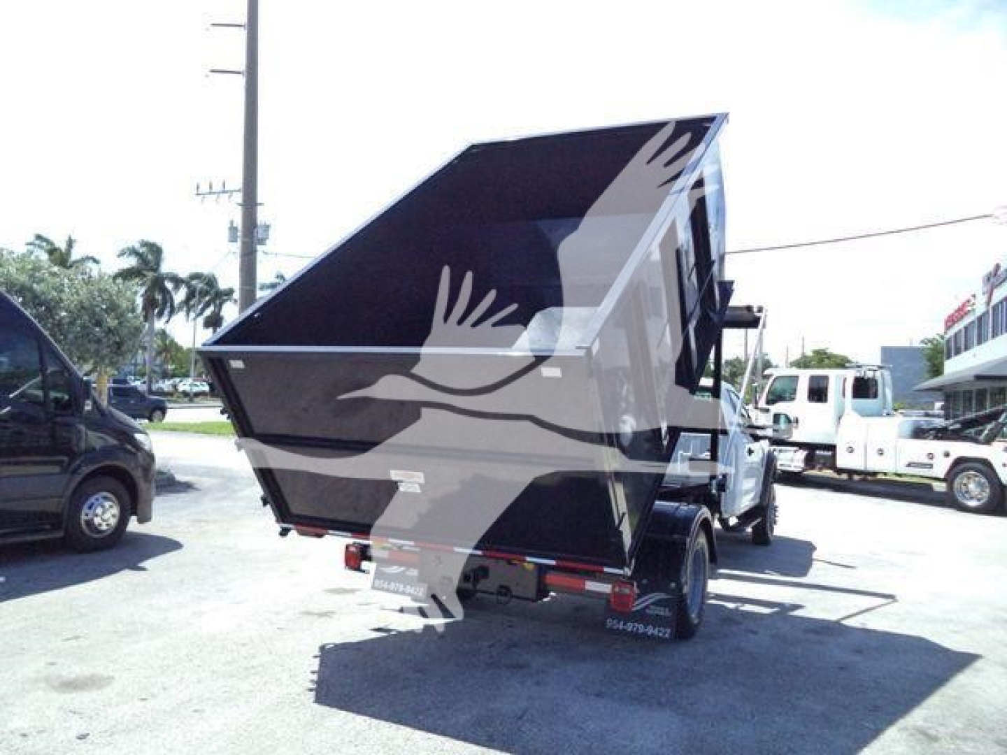 Ford F-550 roll-off truck bed lifted in rear view showing dump bed and chassis with rear wheels.