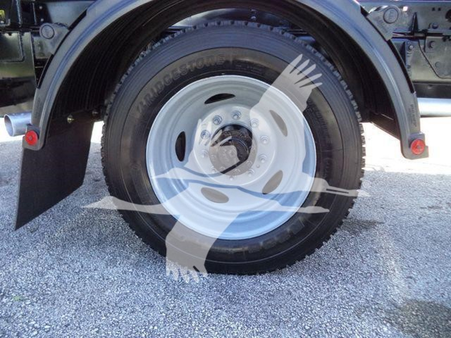 Ford F-550 wheel well and tire showing rim and hub, part of a rolloff truck.