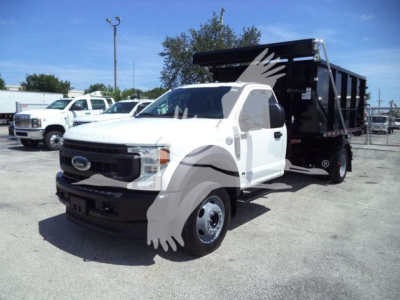 Ford F-550 dump truck in a dealership lot, front-left view showing white cab, black grille, and black dump bed.