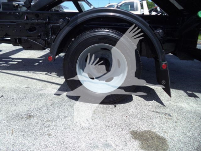 Ford F-550 roll-off truck rear wheel and fender area showing spare wheel, undercarriage, and chassis components.