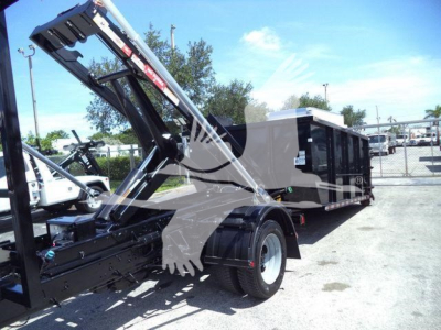 Ford F-550 roll-off truck with raise/lift mechanism and black service body, side view showing rear wheels and hydraulic arm.