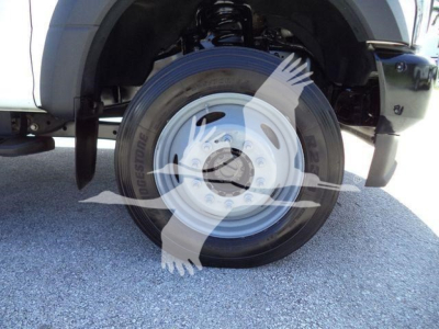 Truck front wheel well showing Bridgestone tire and steel rim; partial fender and suspension visible.