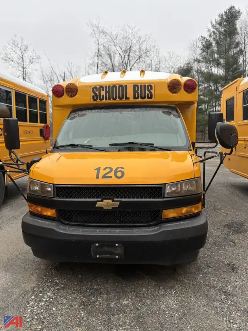 School bus front view showing bright yellow Chevrolet Express G3500 with 126 on hood and 'SCHOOL BUS' sign on roof; two side mirrors and headlights visible.