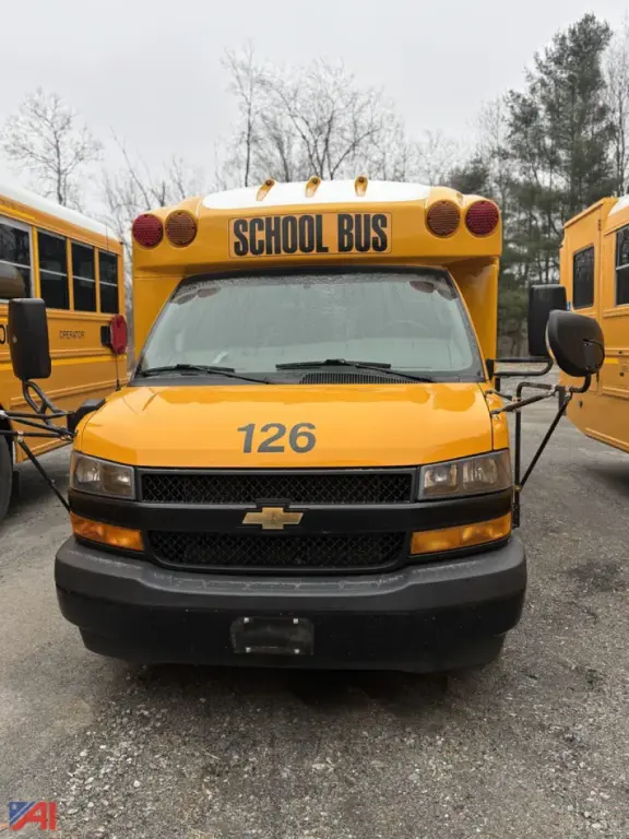 School bus front view showing bright yellow Chevrolet Express G3500 with 126 on hood and 'SCHOOL BUS' sign on roof; two side mirrors and headlights visible.