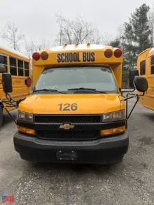 School bus front view showing bright yellow Chevrolet Express G3500 with 126 on hood and 'SCHOOL BUS' sign on roof; two side mirrors and headlights visible.
