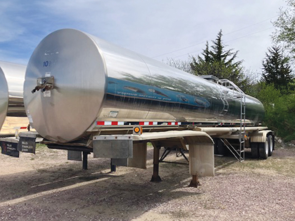 Tank trailer showing reflective stainless steel tanker with ladder and support legs.