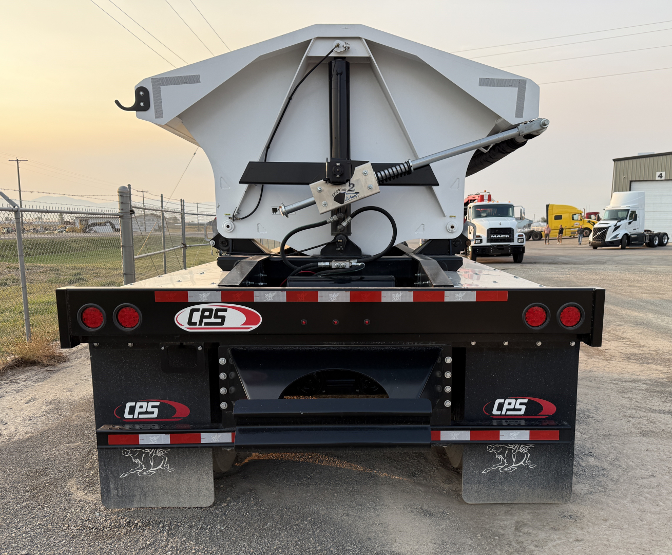 Back view of a 2025 Manac 42' tri-axle trailer showing CPS branding, red/white reflective tape, and mud flaps with logos. Visible text includes CPS logos on the bumper and mud flaps, and a heavy-duty hydraulic mechanism in the center.