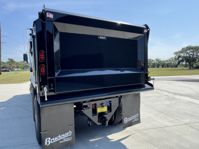Dump truck bed showing rear view with black dump body and tailgate, Buckners Bucket full trailer equipment mud flaps, and hydraulic hookups.