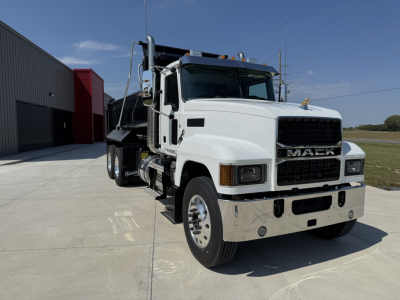 Mack PI64 dump truck in white front-quarter view showing chrome bumper, grille with MACK lettering, dual rear wheels, and dump bed.
