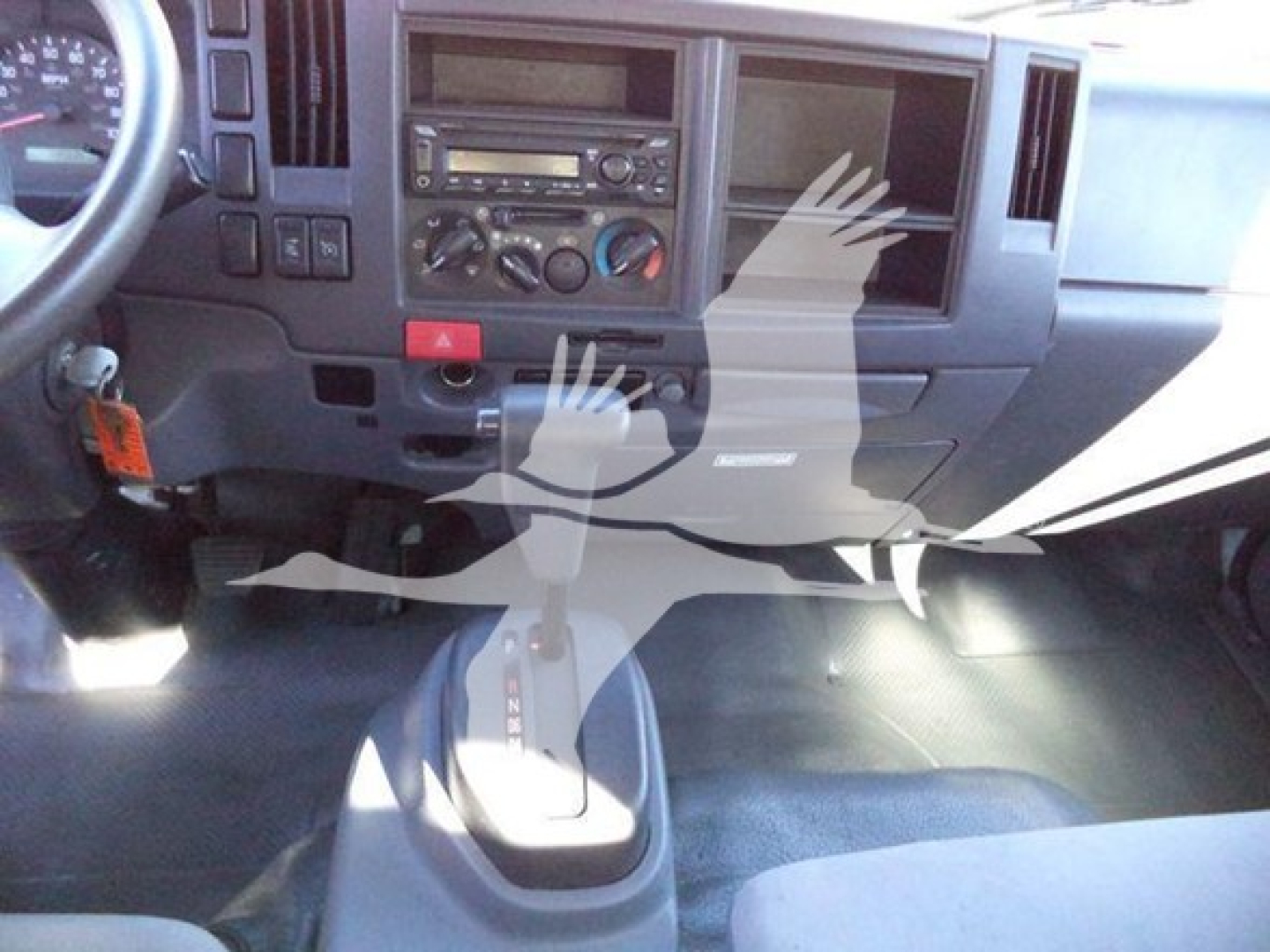 Dashboard view of a 2020 Isuzu NPR HD cab showing steering wheel, center console, climate controls, radio, and gear shifter.