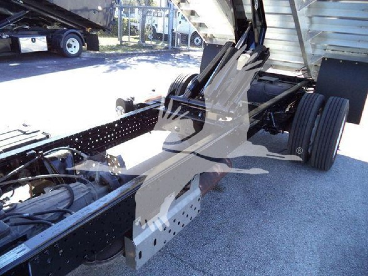 Isuzu NPR-HD truck chassis and lifting mechanism showing frame rails, hydraulic lines, and rear wheels.
