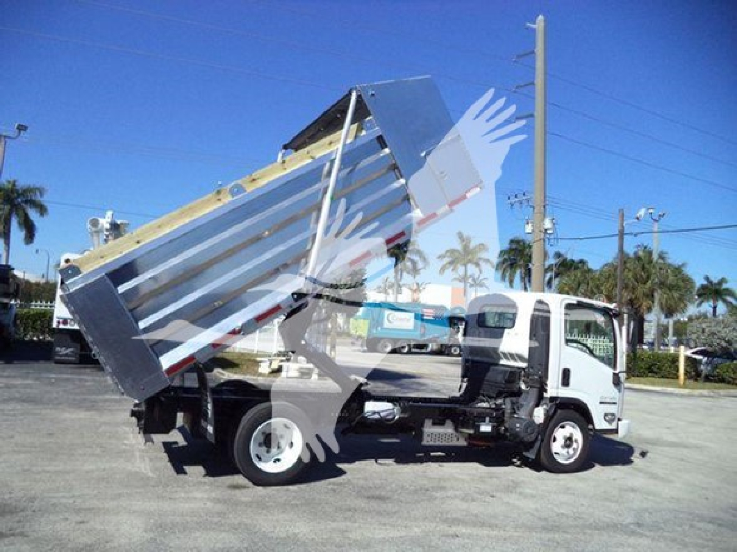Isuzu NPR HD dump truck in service lifting its aluminum dump bed at an angle.