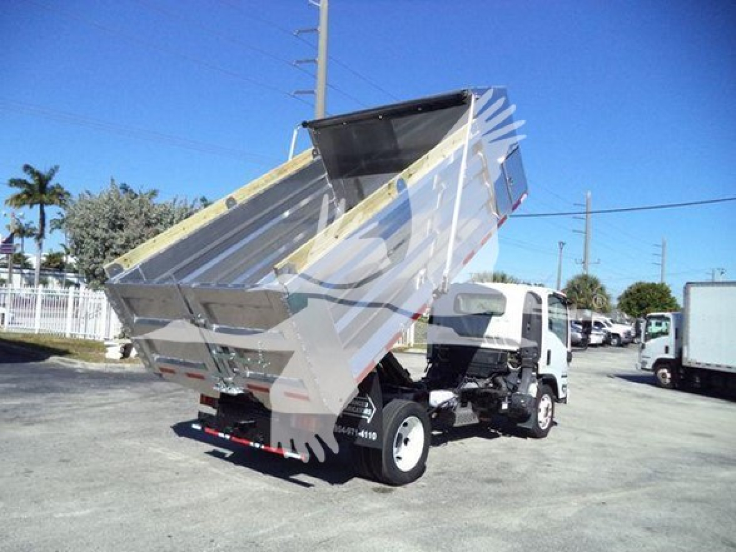 Isuzu NPR-HD dump truck with bed raised, side view showing truck bed and hydraulic mechanism.