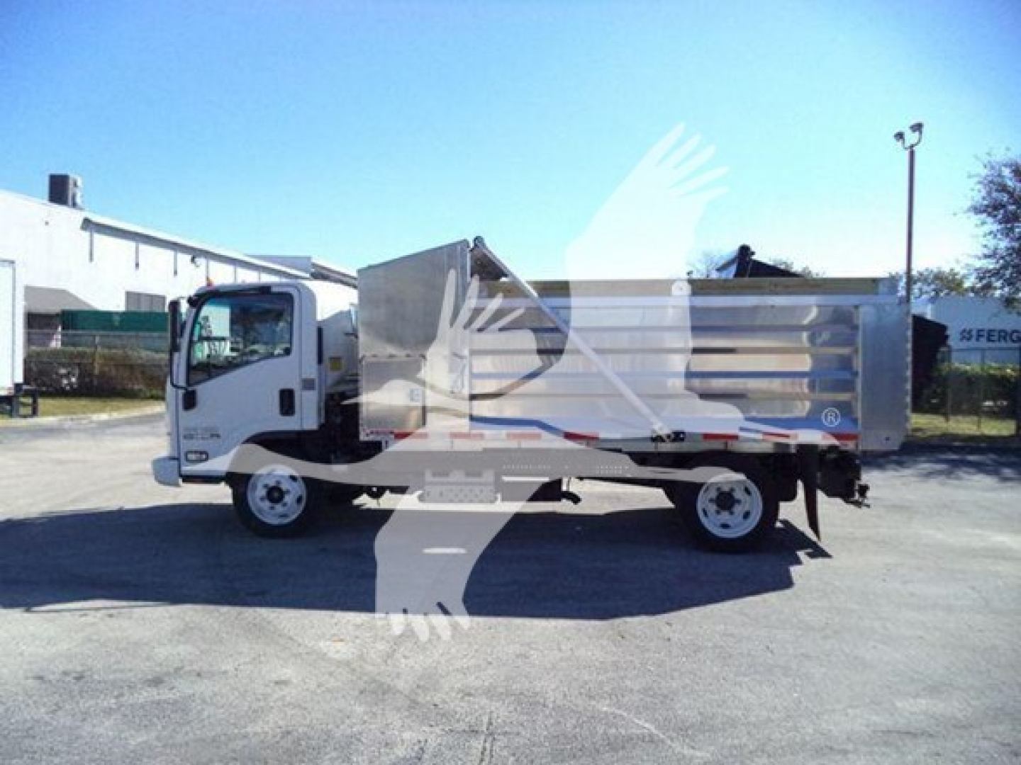 Isuzu NPR HD dump truck side view with white cab and silver dump bed, in-service vehicle.