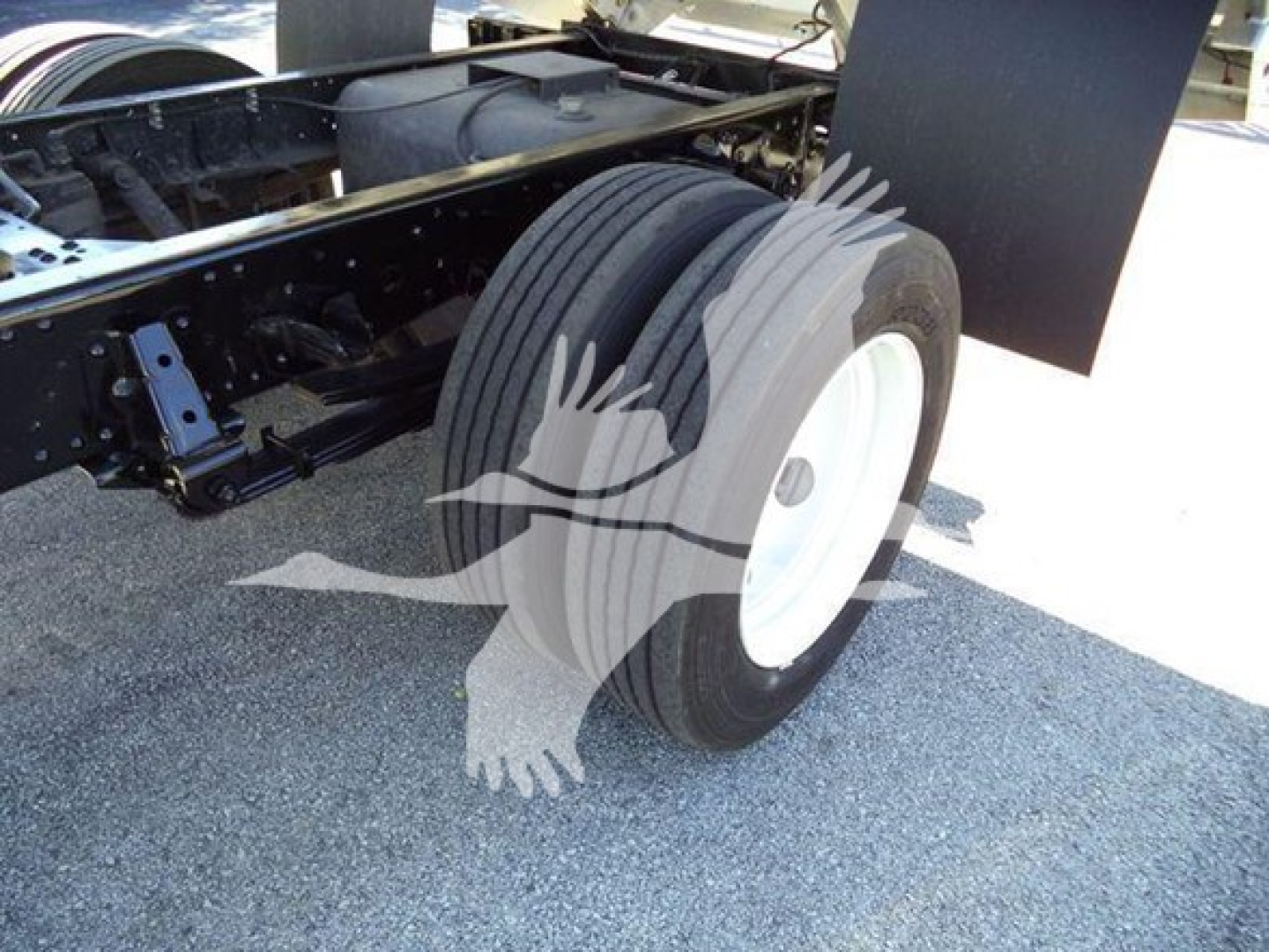 Isuzu NPR HD truck chassis showing front dual rear wheels and suspension; white steel wheel with black tire and chassis framing visible.