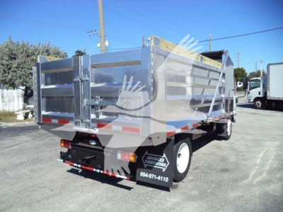 Isuzu NPR-HD dump truck bed in rear three-quarter view showing metallic cargo bed with reflective stripes and rear bumper.
