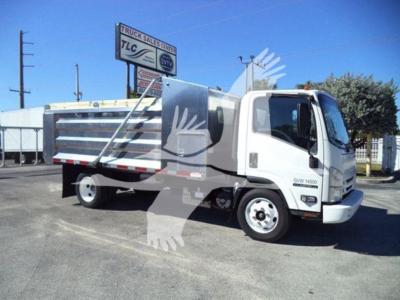 Isuzu NPR HD truck in a used condition, side view showing utility dump bed and cab with white paint.