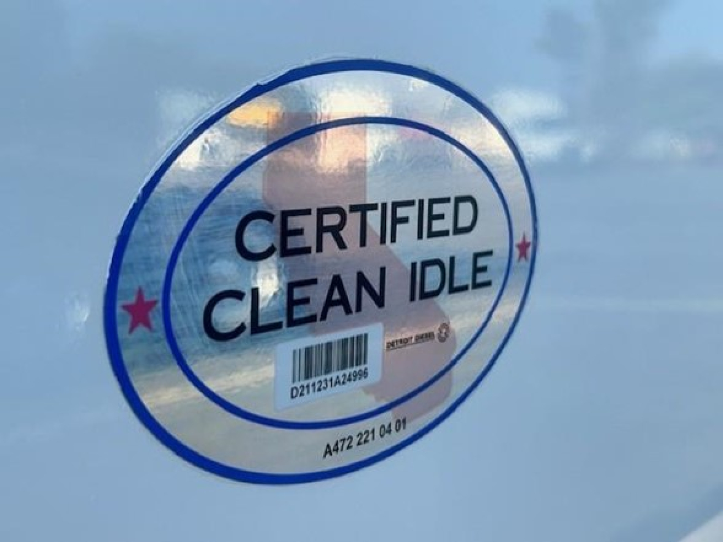 Certified Clean Idle sticker on curtain side of a Freightliner Cascadia 126 showing a circular blue seal with the words CERTIFIED CLEAN IDLE and a barcode beneath.